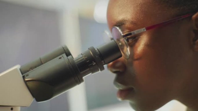 从事显微镜工作的非洲女科学家。脸部特写
