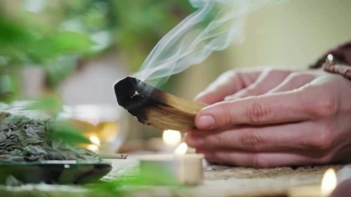 女人的手燃烧帕洛桑托木棍。烟雾用于冥想和清除