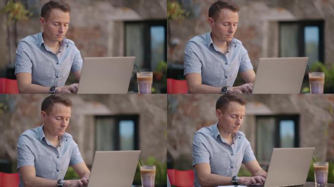 戴眼镜的英俊自由职业者在咖啡馆勤奋地在笔记本电脑上工作。男子在键盘上打字，并在咖啡店的互联网上搜索新