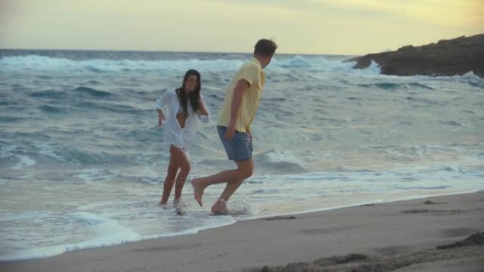 海滩上的浪漫情侣。恩爱的情侣牵手玩浪