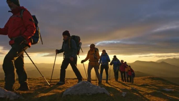 空中SLO MO一群人在日落时徒步穿越山顶
