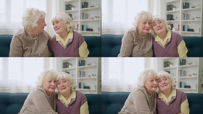 两个美丽的老年妇女在沙发上拥抱的肖像，姐妹，灵魂伴侣