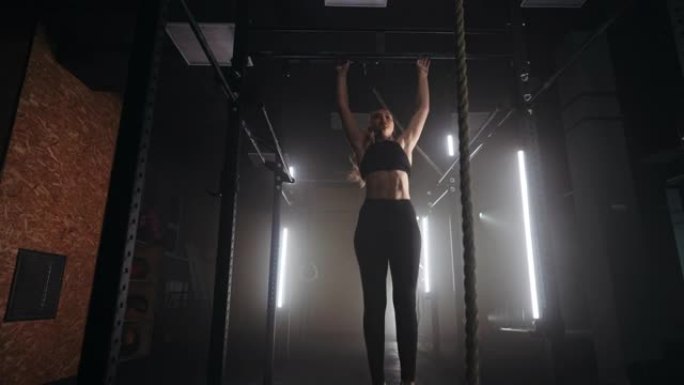 运动女子在健身房的横杆上进行引体向上，女性身体摇摆的慢动作拍摄