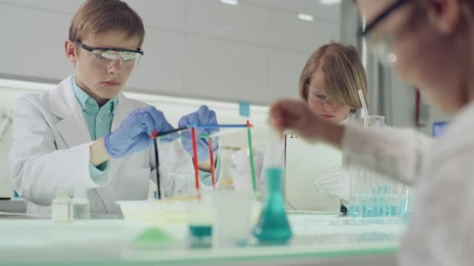 孩子们在实验室进行科学实验。用肥皂泡液体研究表面张力，做笔记