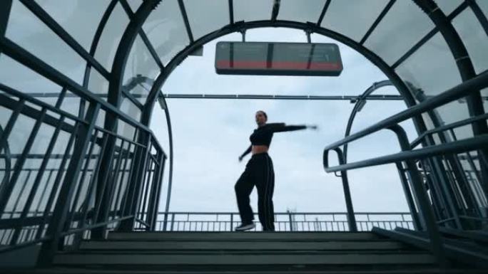美丽的年轻女舞者正在火车站表演现代舞蹈，剪影