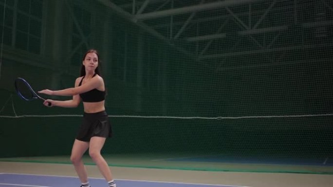 年轻女子在室内球场上打网球，用球拍击球，在比赛中慢动作