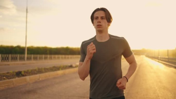 中号跑男肖像在阳光明媚的早晨，运动员在空旷的路上慢跑，独自训练