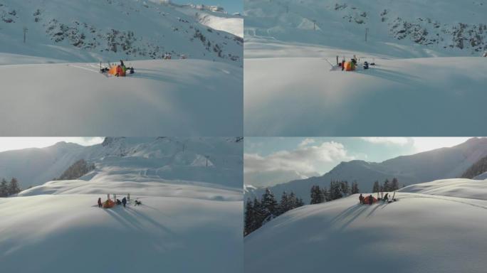一群滑雪者在雪山上的帐篷周围的空中无人机拍摄