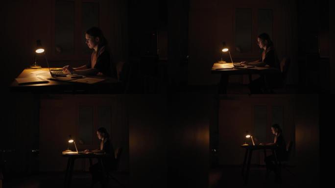 晚上在灯下的女人在黑暗中在家工作。工作截止日期的晚上时间是紧迫的截止日期。