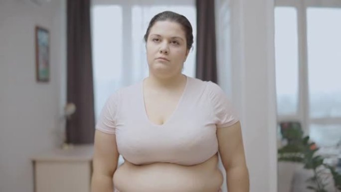 心烦意乱的超大女人看着卷尺，腰围发胖，失重