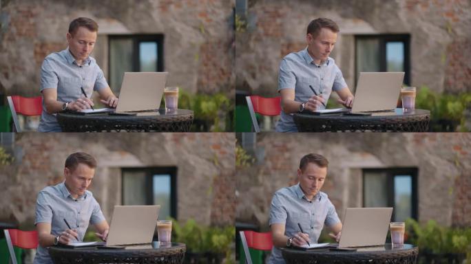 一个坐在街头咖啡馆里的男人在笔记本上远程写笔。在笔记本电脑上工作。一名男子在笔记本电脑上远程工作