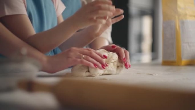 小女孩正在学习做饭，揉面团做蛋糕或面包，母亲正在帮助女儿，特写镜头