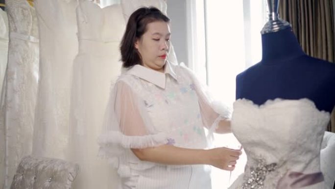 小型企业的婚礼服装业务，在商店里缝制白色婚纱。