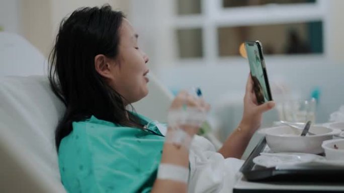 生病的亚洲妇女通过手机视频通话与朋友交谈
