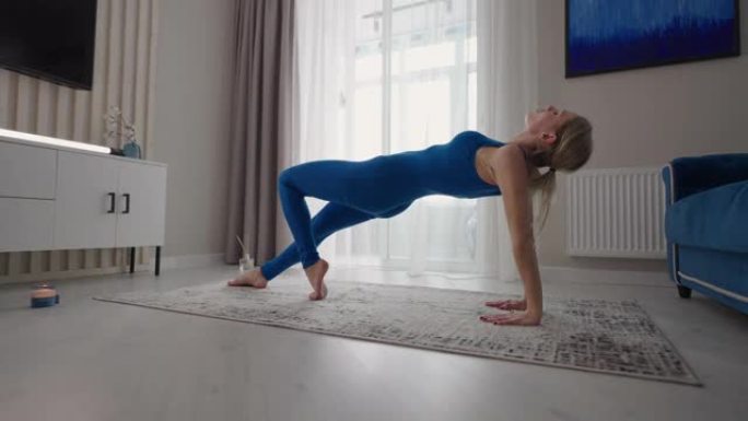 女性在家做瑜伽练习，伸展灵活的身体，把手放在垫子上。女运动员在客厅进行健身训练，享受体育锻炼健康的生