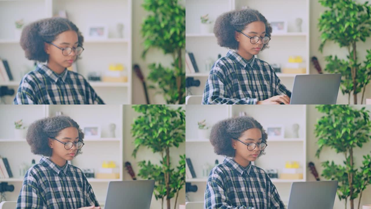 聪明的黑人少女在眼镜上打开笔记本电脑，为学校做作业
