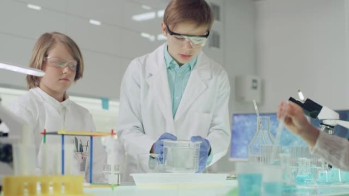 孩子们进行科学实验。实验室内部，倒多色液体，检查结果