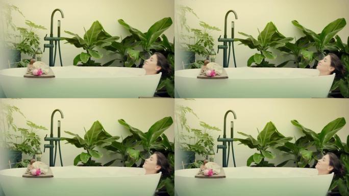 年轻女子在浴室内郁郁葱葱的绿色花园里泡泡浴
