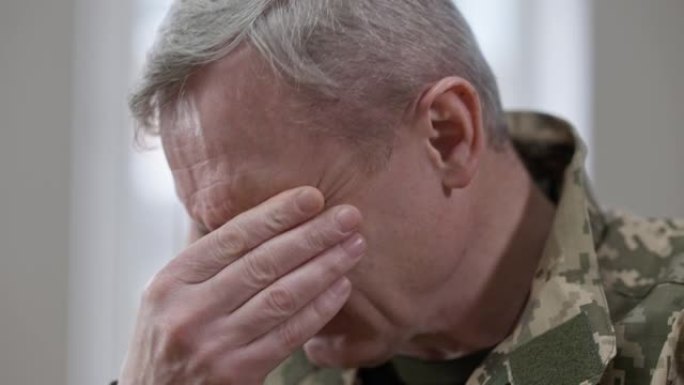 一名中年白人军人在室内哭泣。近距离肖像沮丧沮丧的老兵在制服。心理健康问题和危机概念。