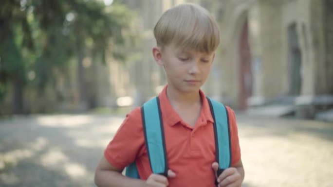 迷人的小男孩背着背包走在校园里的肖像。金发碧眼的白人可爱的男生在阳光明媚的夏日漫步在户外。Z世代。