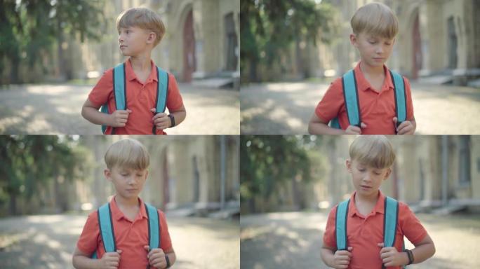 迷人的小男孩背着背包走在校园里的肖像。金发碧眼的白人可爱的男生在阳光明媚的夏日漫步在户外。Z世代。