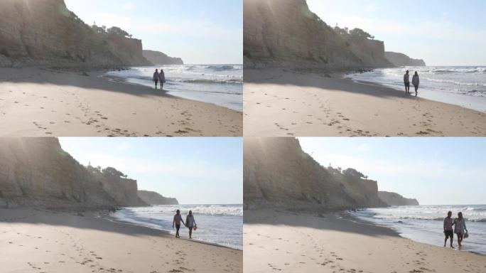 夫妇沿着空荡荡的海滩散步，日出