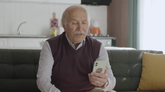 老人在他家的客厅用智能手机上网。