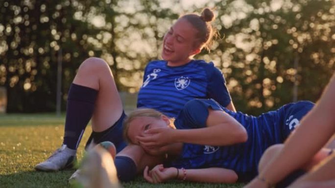 SLO MO两名女足球运动员坐在运动场上笑着