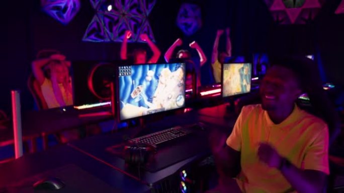 非洲民族职业玩家男孩参加电子游戏eSport锦标赛。对着摄像机摆姿势，背景团队
