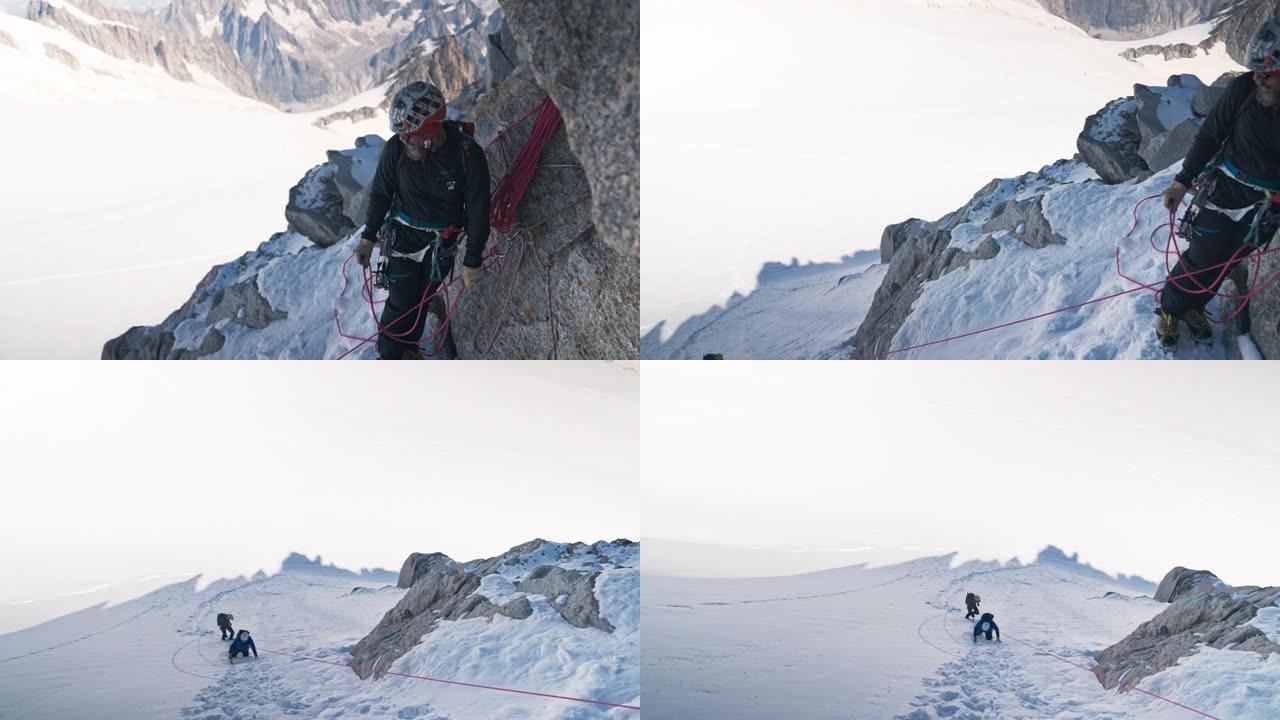 一队登山者在陡峭的山峰上移动。使用绳索和攀爬设备。远景
