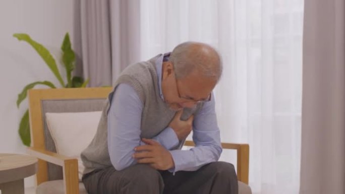 亚洲老人因心脏病而胸痛在客厅的沙发上。