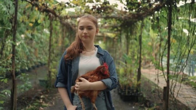 十几岁的女孩在有机农场工作时抱着鸡