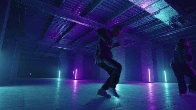 两名时尚的专业男女舞者在虚拟制作工作室环境中表演嘻哈舞蹈。男女嘻哈在黑暗的工作室里用烟雾和灯光移动。