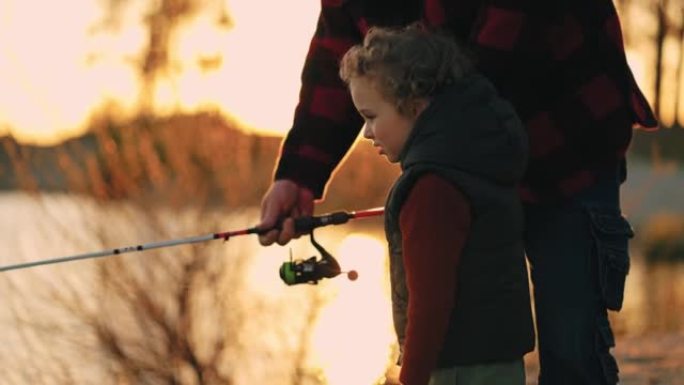 小男孩和他的父亲在日落时分一起在河边或湖岸钓鱼