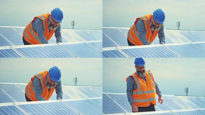 在屋顶光伏太阳能发电厂的光伏面板上工作的男性工程师