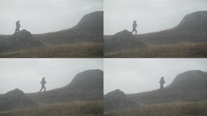 女越野跑运动员在草地上的雾气中奔跑，后面是白雪皑皑的山峰