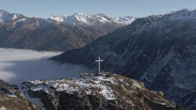 空中无人机在被山脉包围的山顶上拍摄十字架