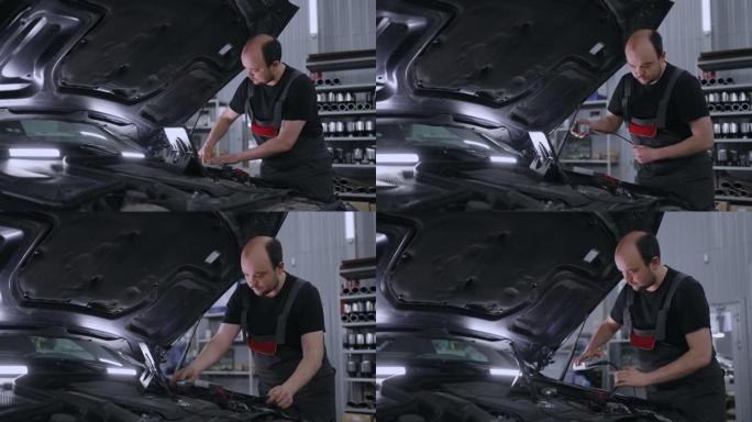 一名男性汽车修理工在汽车服务中使用计算机检查汽车的引擎盖