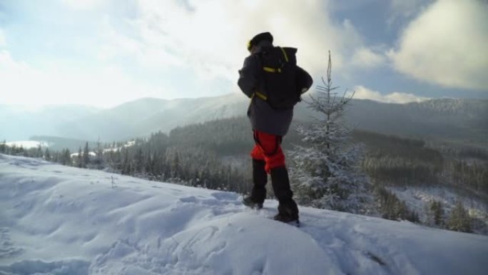 男性徒步旅行者徒步进入冬季山地景观