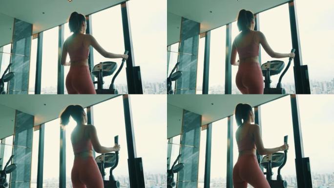 后视图: 美女在健身房用椭圆步行机锻炼