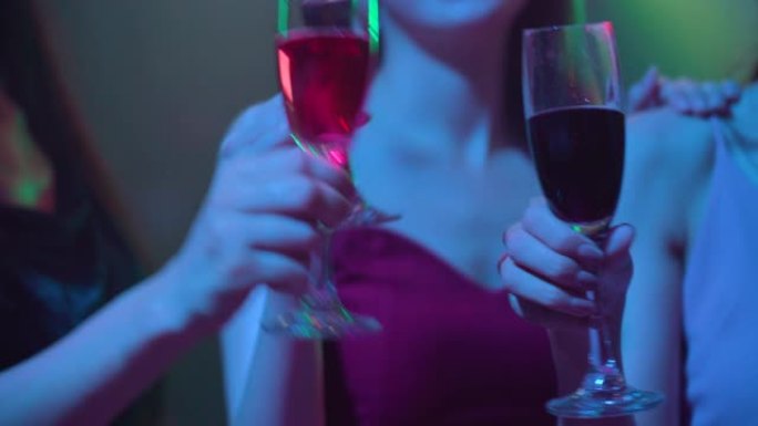 女性朋友手持一杯香槟在夜总会跳舞