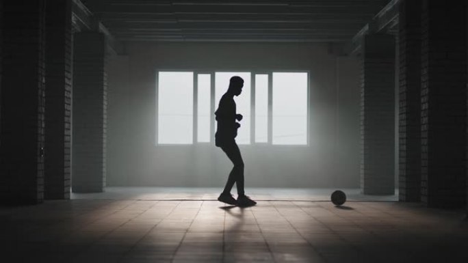 一名男子在阳光下慢动作将足球踢入地下停车场的墙壁