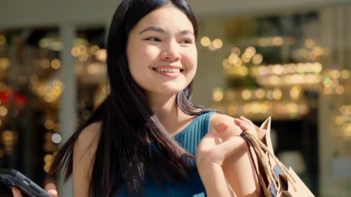 亚洲女人在节日期间在户外购物中心散步和微笑购物。