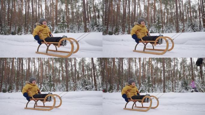 快乐的孩子男孩坐在木制雪橇上，在冬天的森林里骑着雪，家庭时间