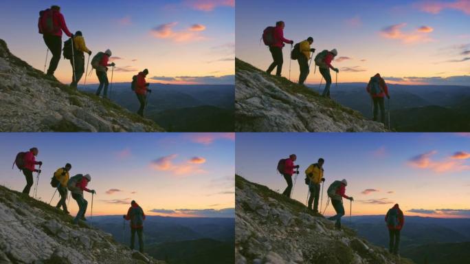 四名徒步旅行者黄昏时在陡峭的斜坡上下山