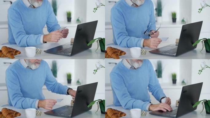 面目全非的大胡子老人在笔记本电脑键盘上打字，拿着名片，摘下眼镜。灰发的高加索退休人员在家室内在线留言