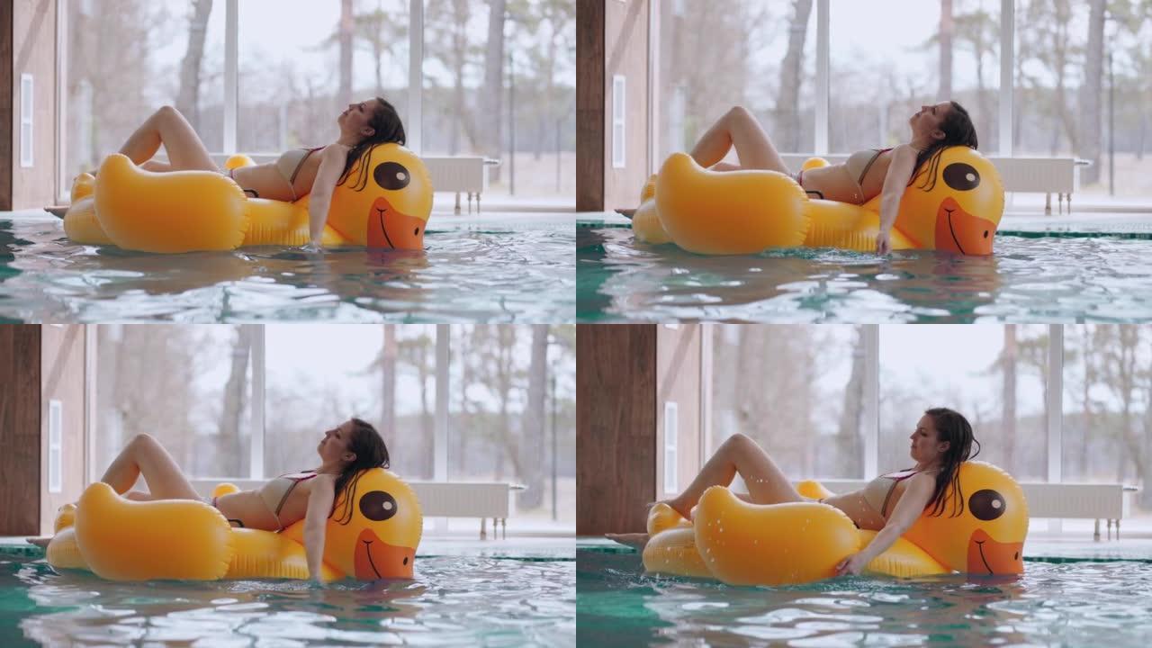 在泳池里放松时间在热水浴中，穿着比基尼的年轻女子躺在充气圈上漂浮
