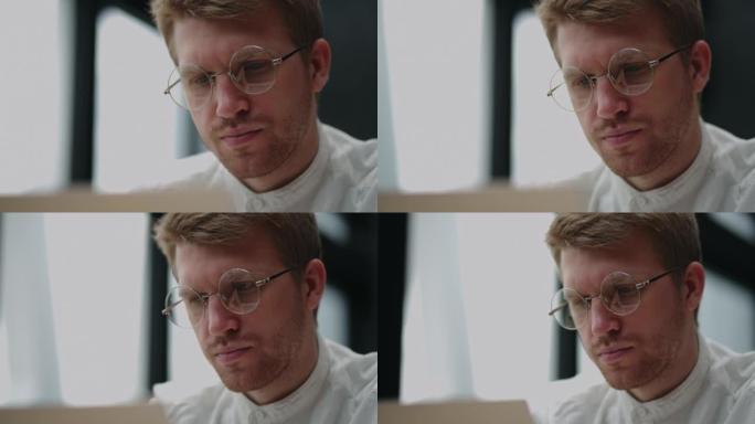 程序员或it专家正在办公室使用笔记本电脑，用眼镜拍摄帅哥的特写肖像