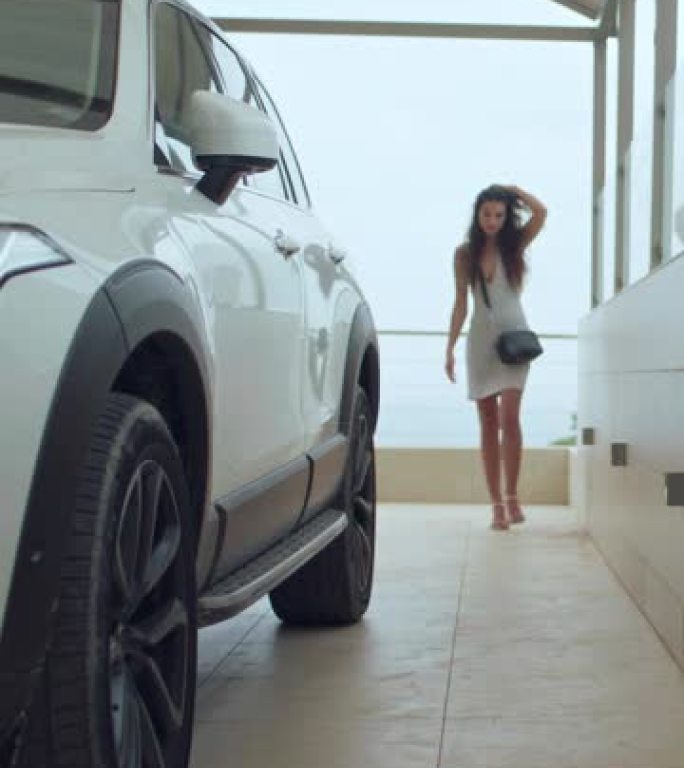 新车停在私人家庭车库里。穿着高跟鞋的有钱女商人进入汽车准备驾驶垂直视频