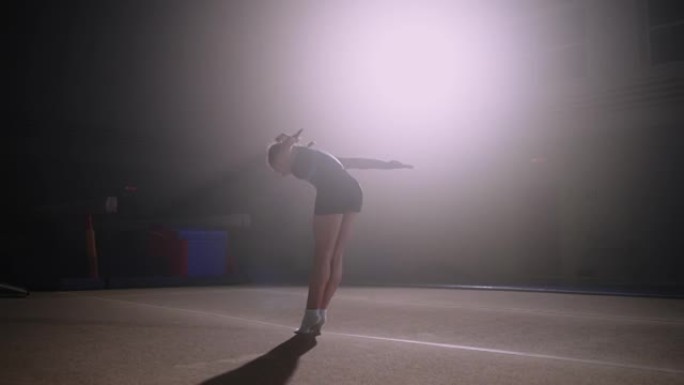 十几岁的女孩体操运动员正在体育馆里表演后空翻，准备参加艺术体操、慢动作、后视比赛